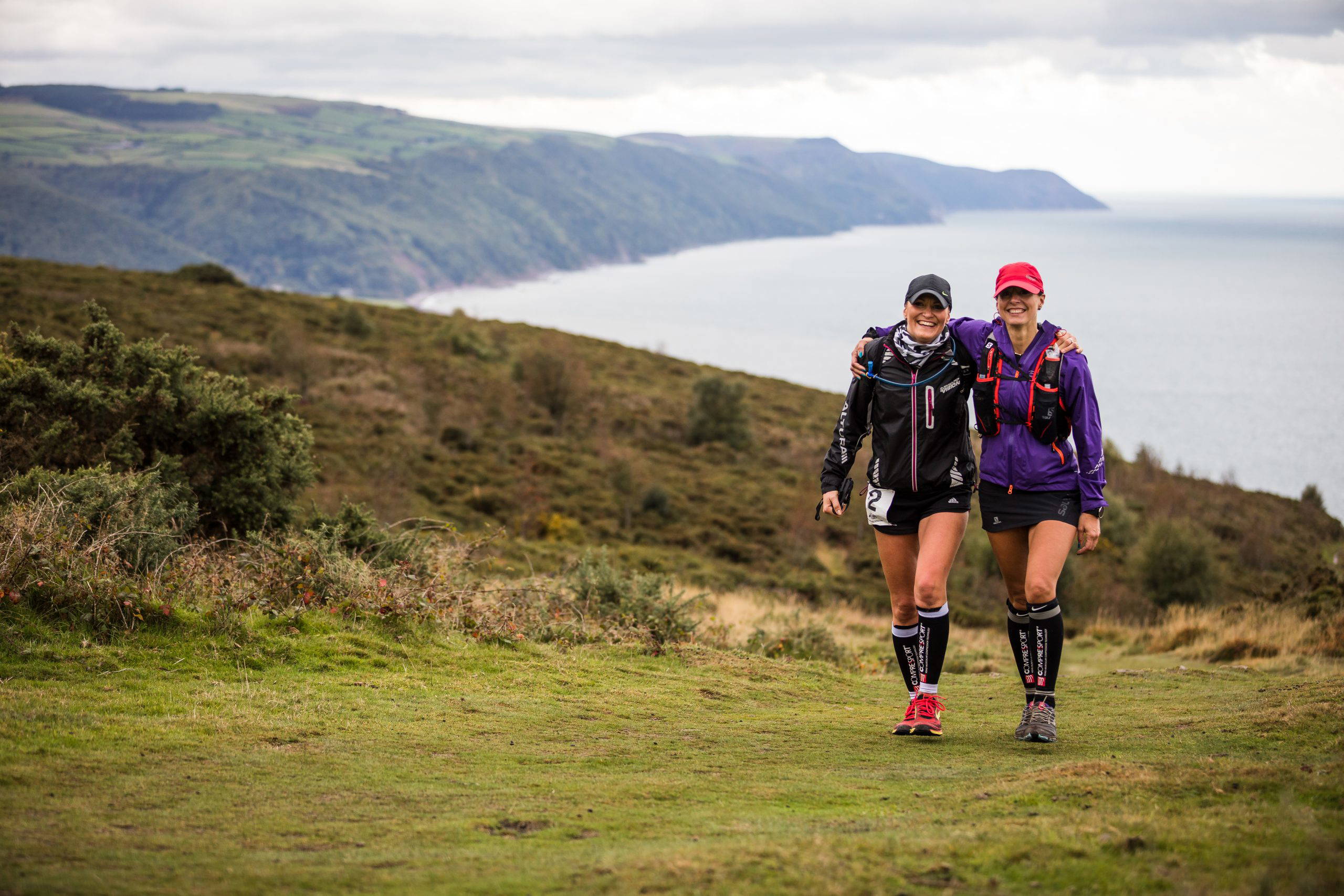 An image of two women arm in arm, walking the moors.