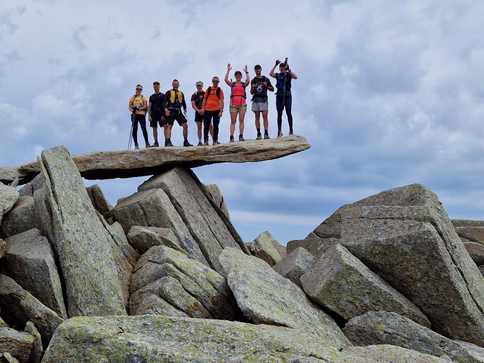 An image of a group of people standing on a balanced boulder.